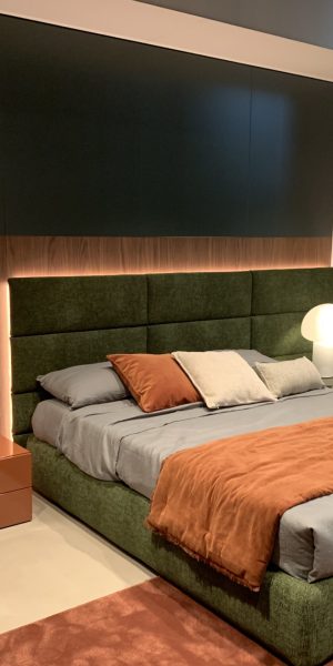 Modern eingerichtetes Schlafzimmer mit grünem Bett und orangen Akzenten.