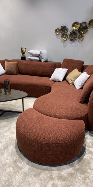 Großes, geschwungenes Sofa in Terrakotta mit dekorativen Kissen.