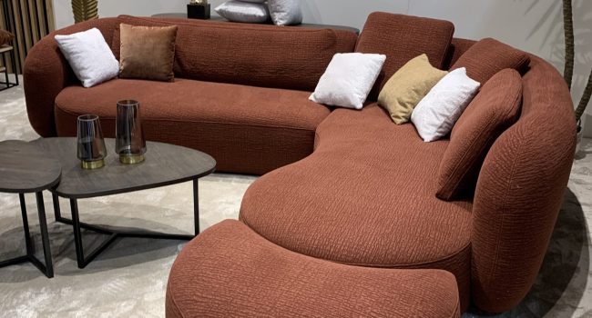 Großes, geschwungenes Sofa in Terrakotta mit dekorativen Kissen.
