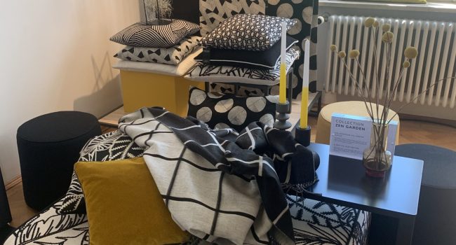 Ausstellung mit schwarz-weiß-gemusterten Stoffen und gelben Akzenten.