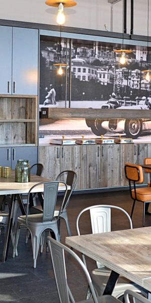 Essbereich mit industriellen Elementen und historischem Motorsport-Bild als Wanddeko.